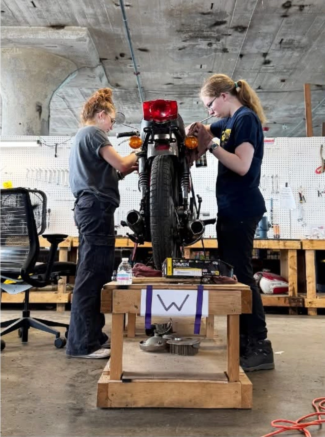 girls working on a vintage motorcycle at engineering summer camp