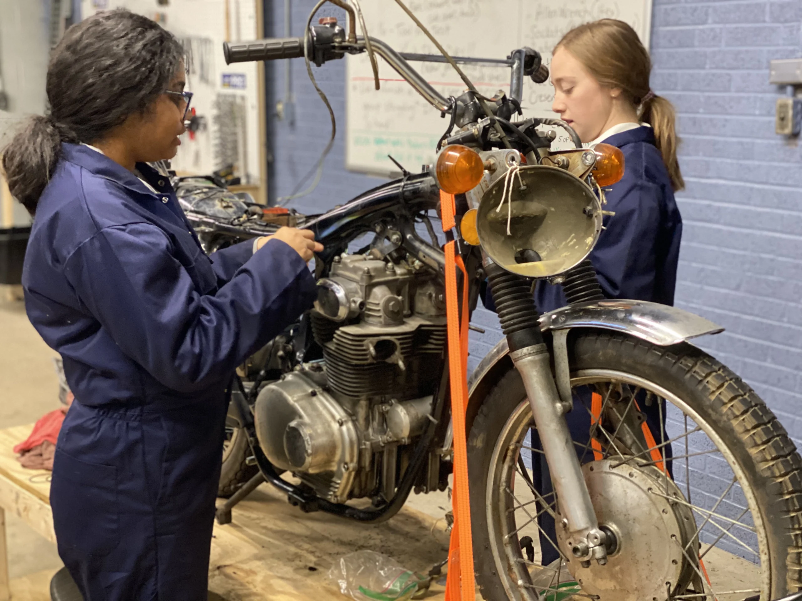 girls working on a vintage motorcycle at engineering summer camp